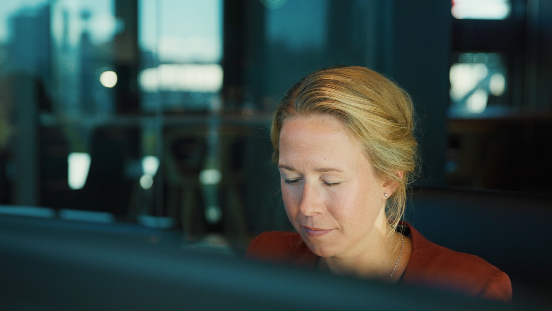 En kvinna sitter framför två datorskärmar på ett höj & sänkbart skrivbord